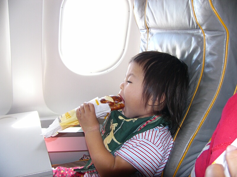 機中でおいしくパンを食べるNAOMI